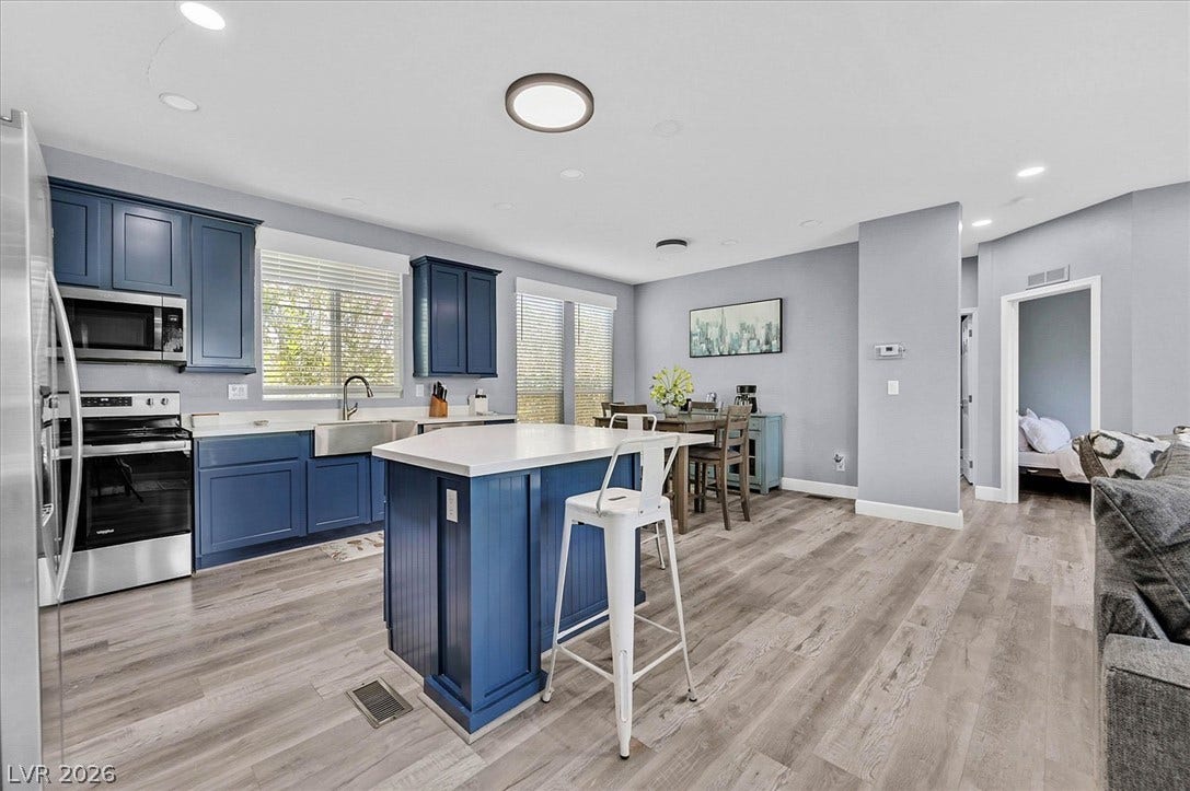 A vibrant kitchen with blue cabinetry and a spacious island seamlessly flows into the dining area.
