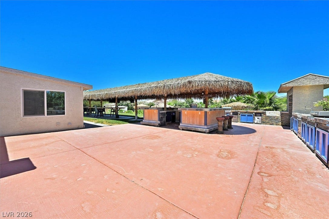 An inviting outdoor kitchen and bar area, perfect for entertaining under the natural shade of a large palapa.