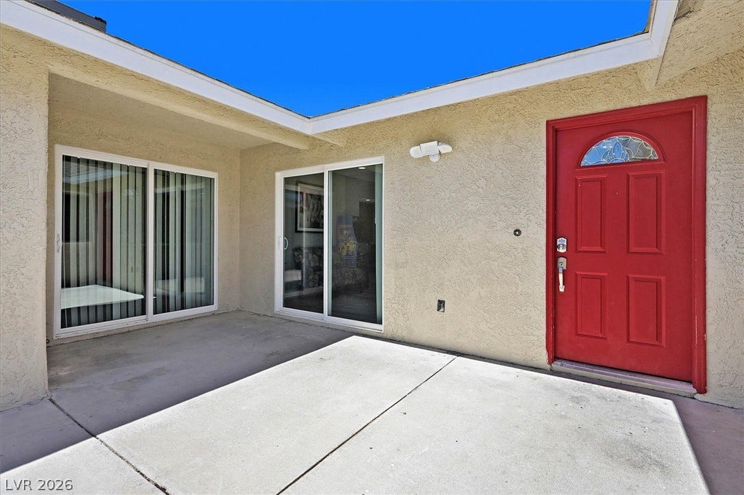 A vibrant entry with a bold red door welcomes you into this property, complemented by sleek sliding glass doors.