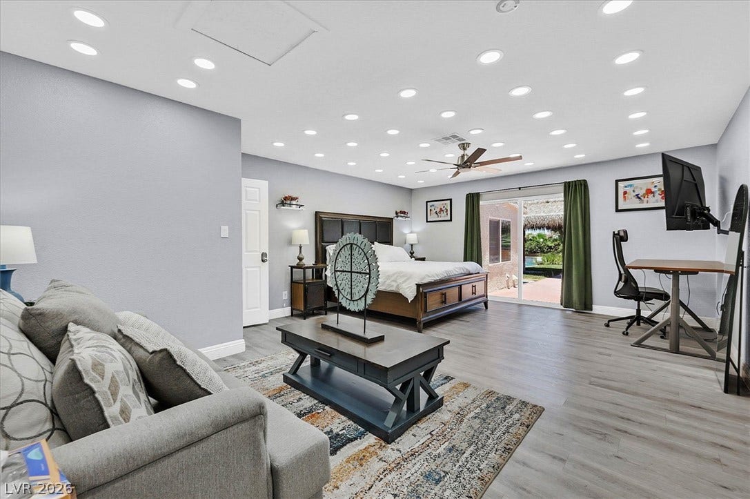Recessed lighting and a ceiling fan illuminate this spacious primary bedroom, featuring direct access to the private yard.