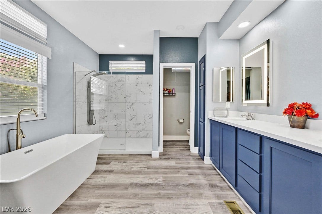 Luxurious bathing quarters feature a spacious walk-in shower, a freestanding tub, and a double vanity.