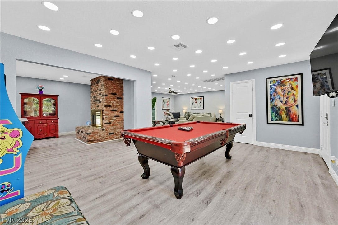 A vibrant game room offers endless entertainment and a cozy brick fireplace.