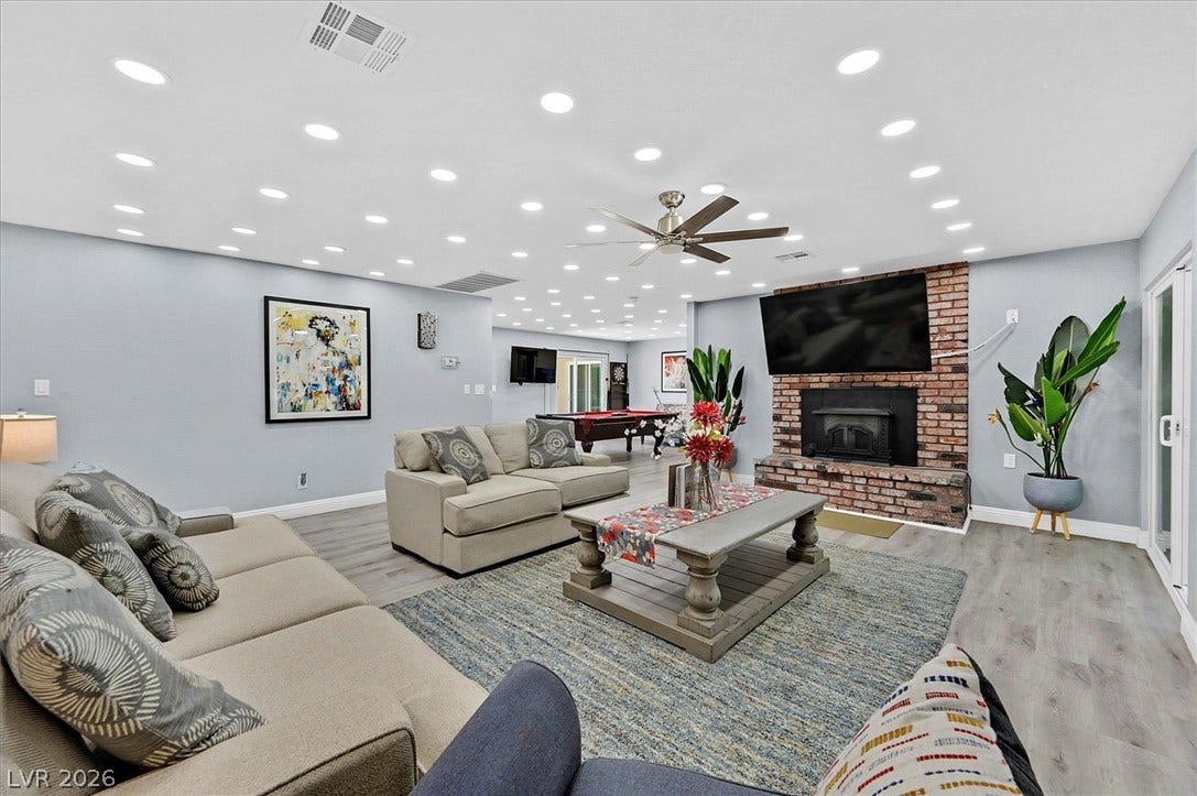 A spacious living area combines comfort and entertainment, featuring a warm brick fireplace.