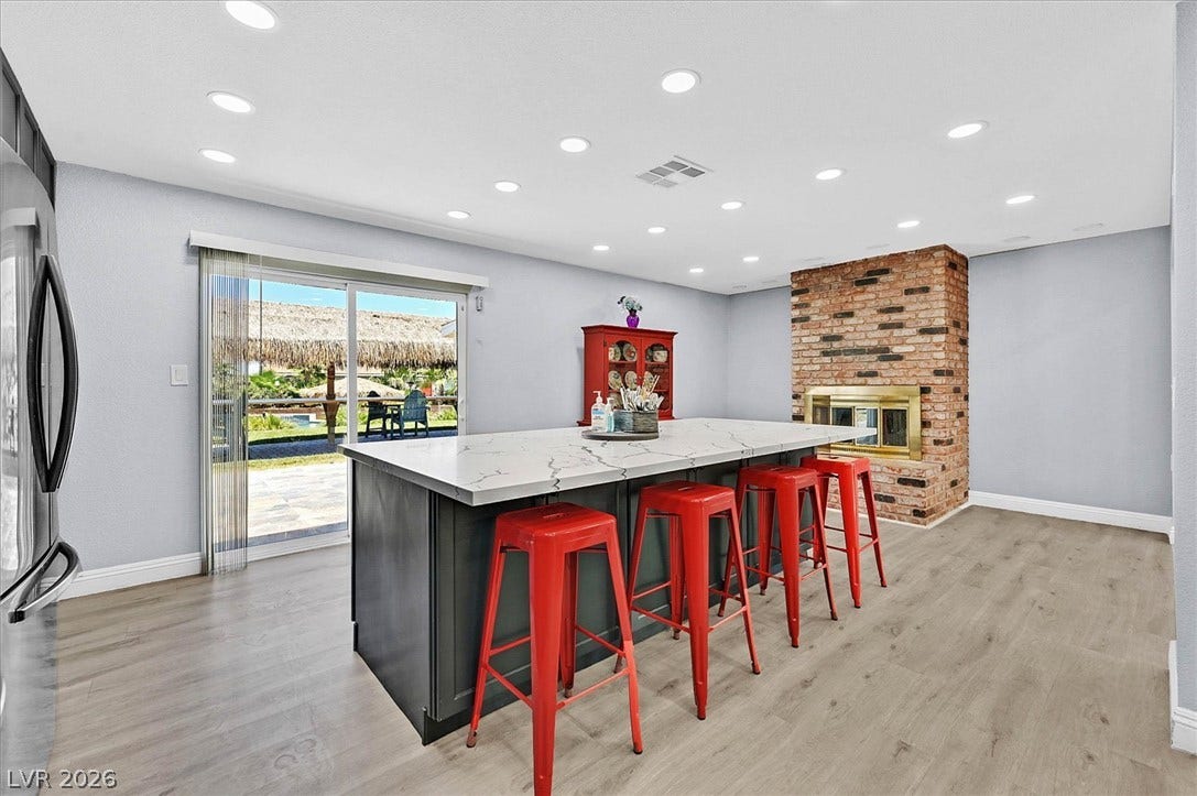 A spacious kitchen with a large island and a brick fireplace, offering direct access to the outdoors.