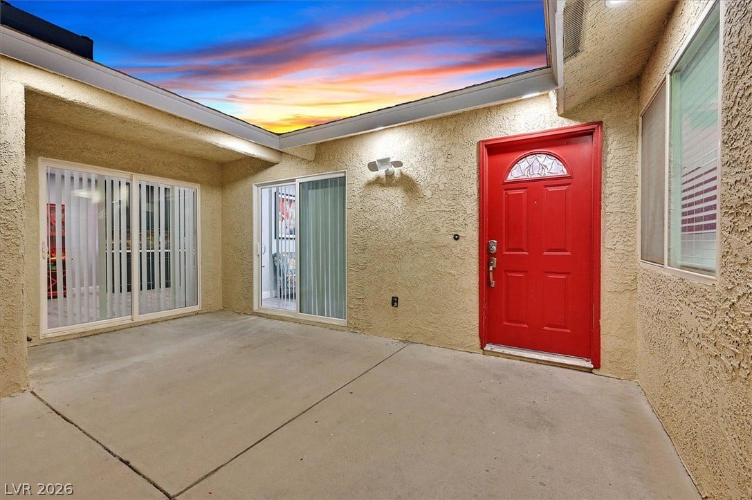 Bold red entry door and dual sliding glass doors welcome you to this private, sun-drenched courtyard.