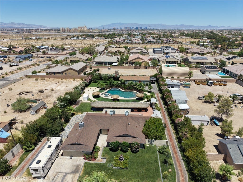 An aerial perspective reveals a spacious estate with a private swimming pool, verdant landscaping, and mountain vistas.