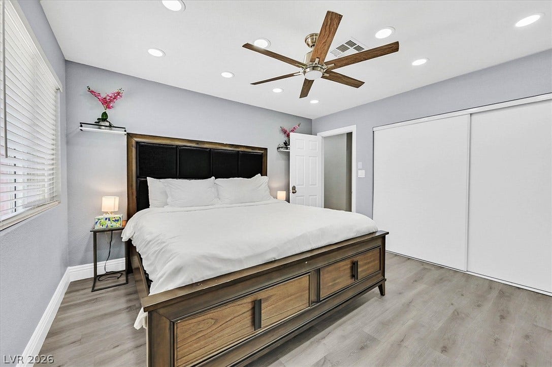 Recessed lighting illuminates this primary bedroom with a contemporary ceiling fan and durable flooring.