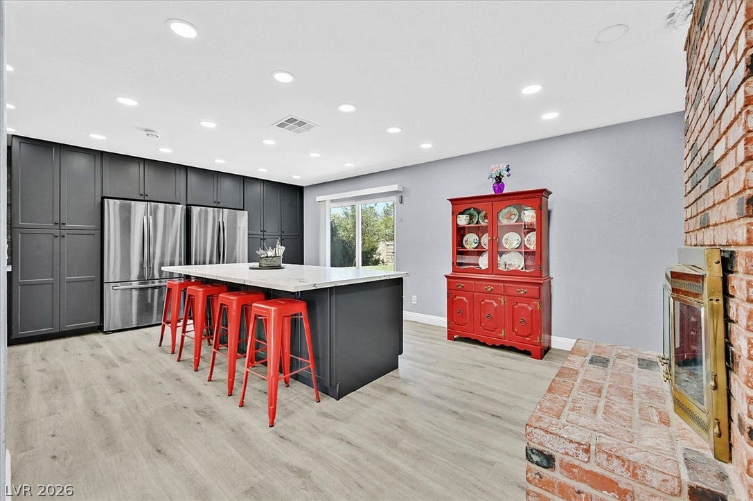 A spacious kitchen with a large central island, recessed lighting, and elegant wood flooring.