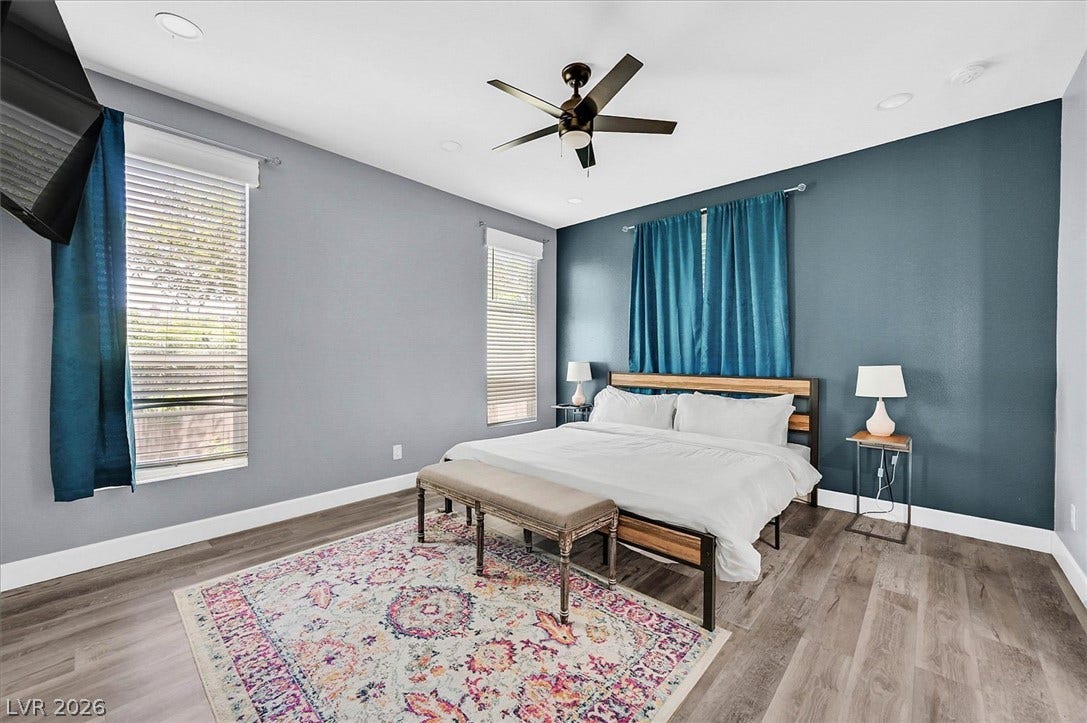 Relax in this tranquil bedroom, featuring a warm wooden floor and a stylish ceiling fan.