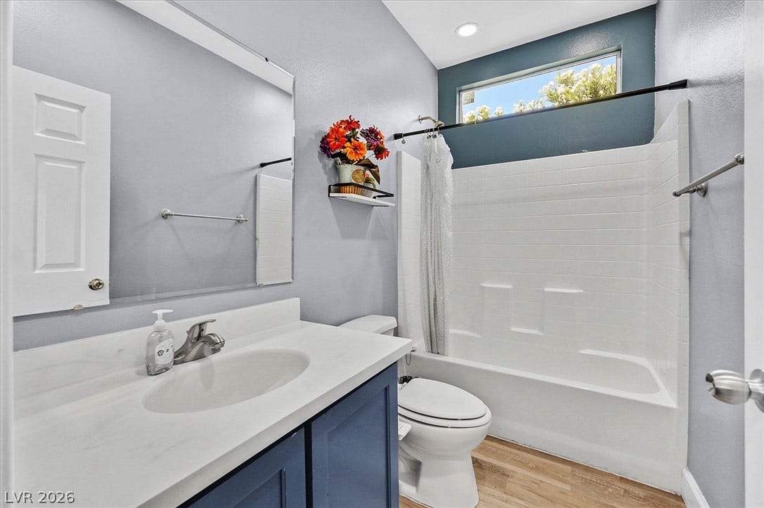 A well-lit bathroom features a white vanity, modern fixtures, and a shower-tub combination.