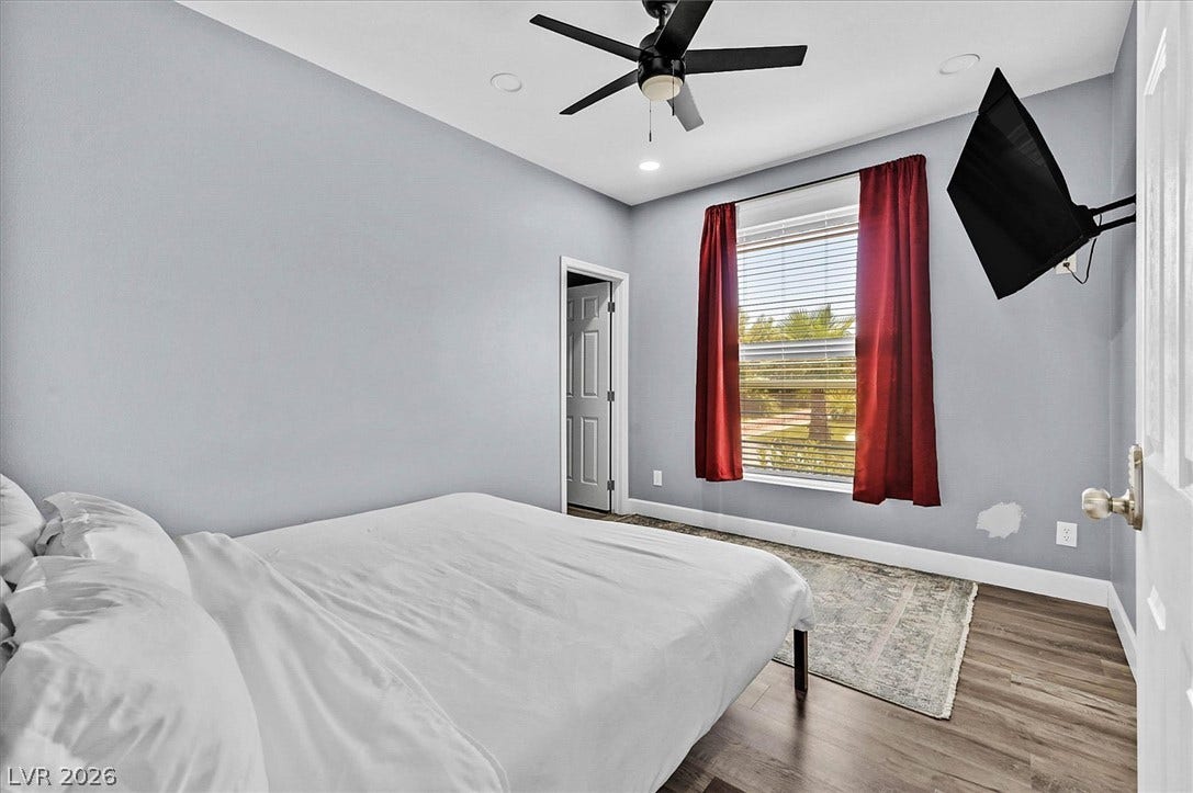 A comfortable bedroom with rich wood flooring and a refreshing ceiling fan for relaxation.
