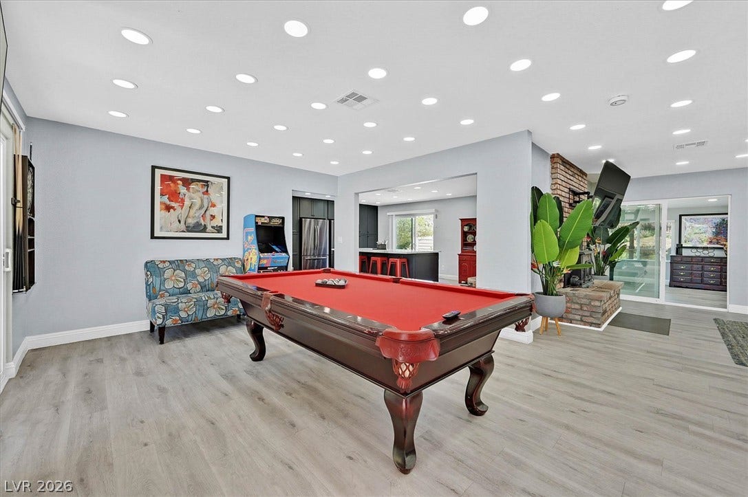 A spacious game room features sleek flooring and ample recessed lighting for lively entertainment.