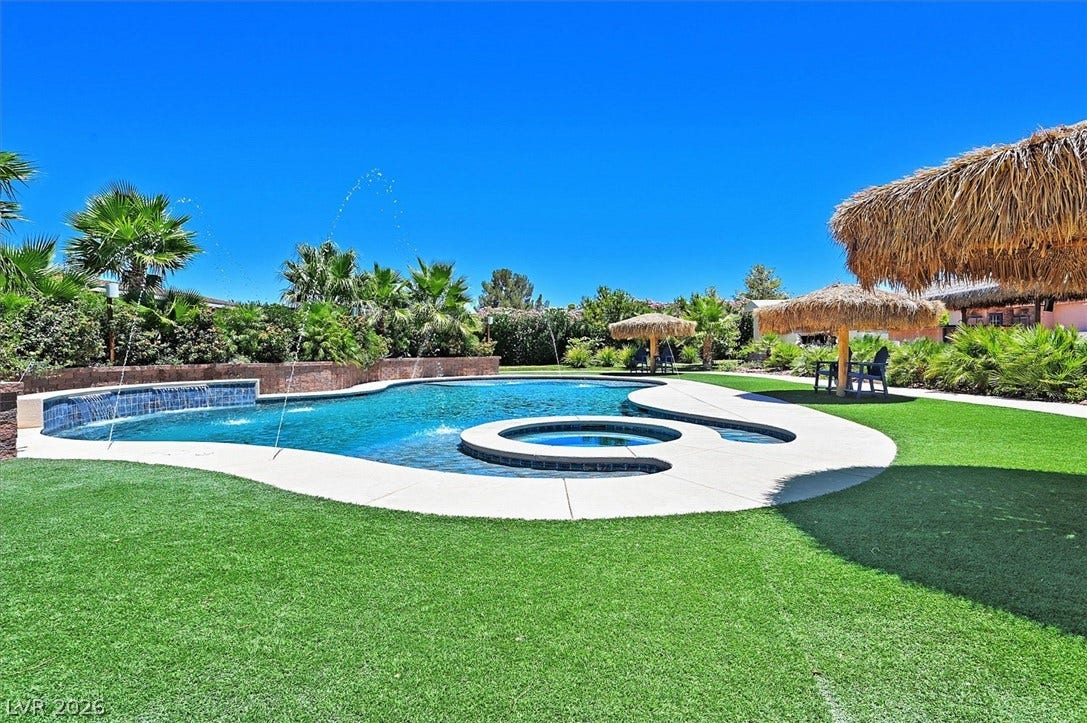 A lavish pool with a waterfall feature and integrated spa creates a backyard oasis.
