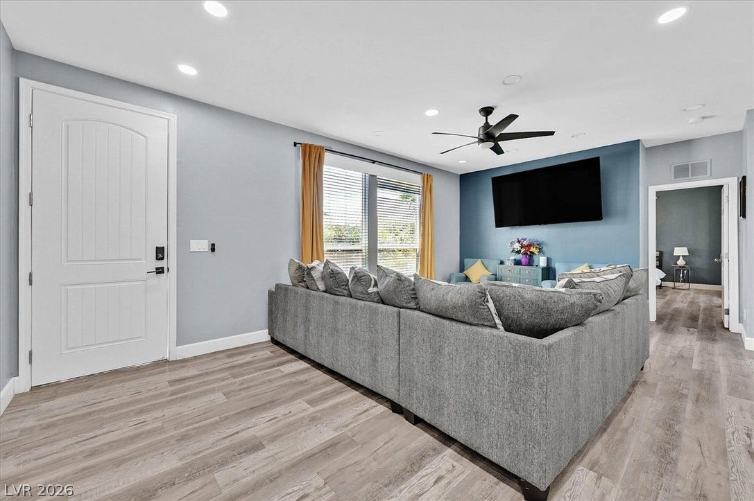 Recessed lighting illuminates this inviting living space, showcasing durable wood flooring.