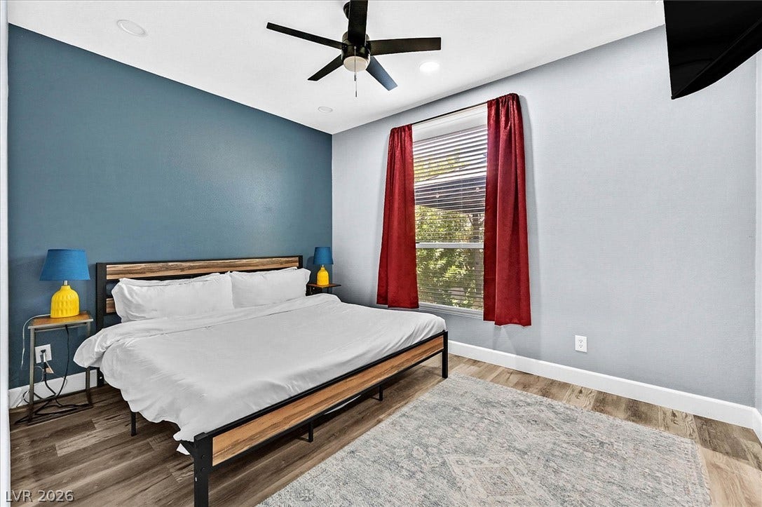 Well-lit room featuring wood-style flooring and a window with vibrant red drapes.