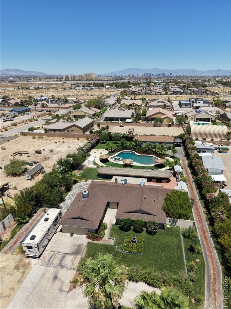 An aerial perspective reveals a lush oasis with a winding pool and meticulously maintained grounds amidst a desert landscape.