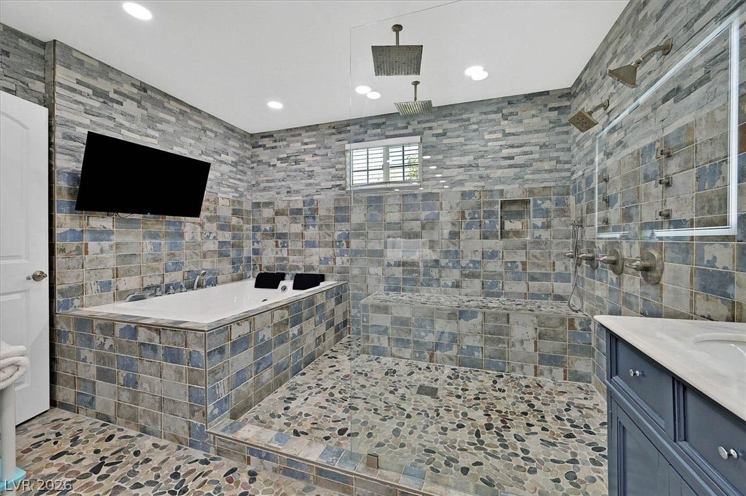 Luxurious bathroom with a spacious soaking tub and an oversized walk-in shower featuring a pebble-tiled floor.