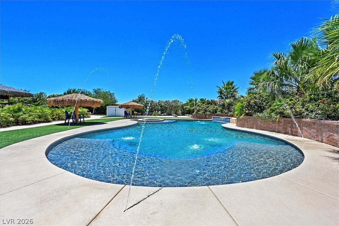 An inviting backyard oasis offers a sparkling pool with water features and mature landscaping.