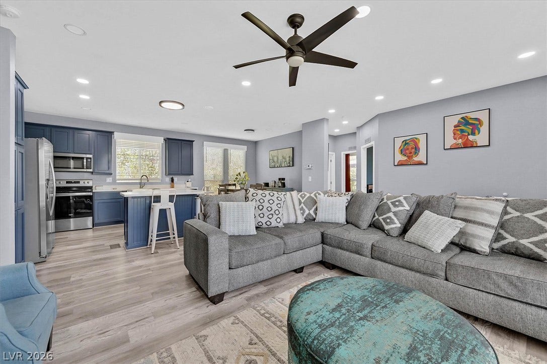 An open concept living and kitchen area features recessed lighting and stylish light wood flooring.