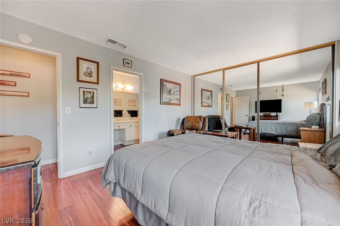 Rich hardwood flooring pairs with expansive mirrored closet doors in this serene bedroom space.
