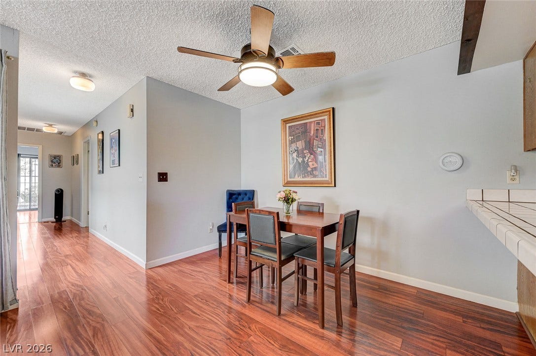 Richly toned wood flooring sweeps through an open dining space and connects adjacent hallways.