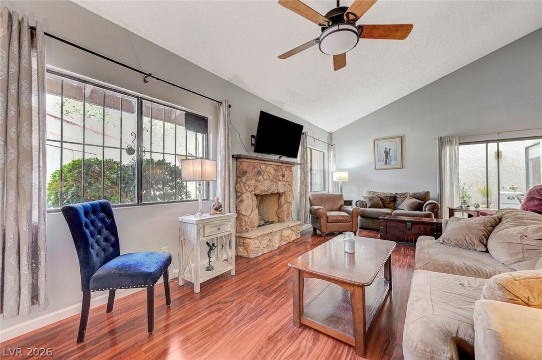 Rich wood floors and a soaring vaulted ceiling frame the cozy stone fireplace.