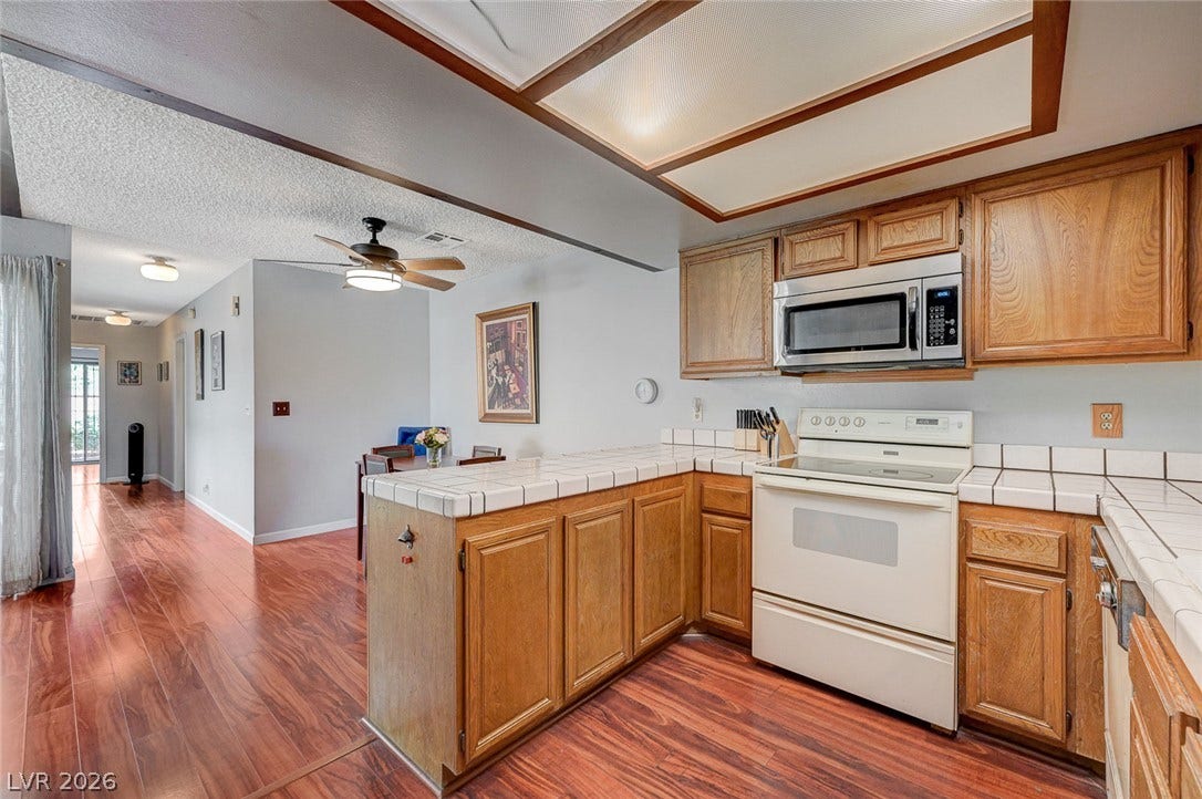 Rich wood cabinetry pairs with tile countertops in this inviting kitchen space.