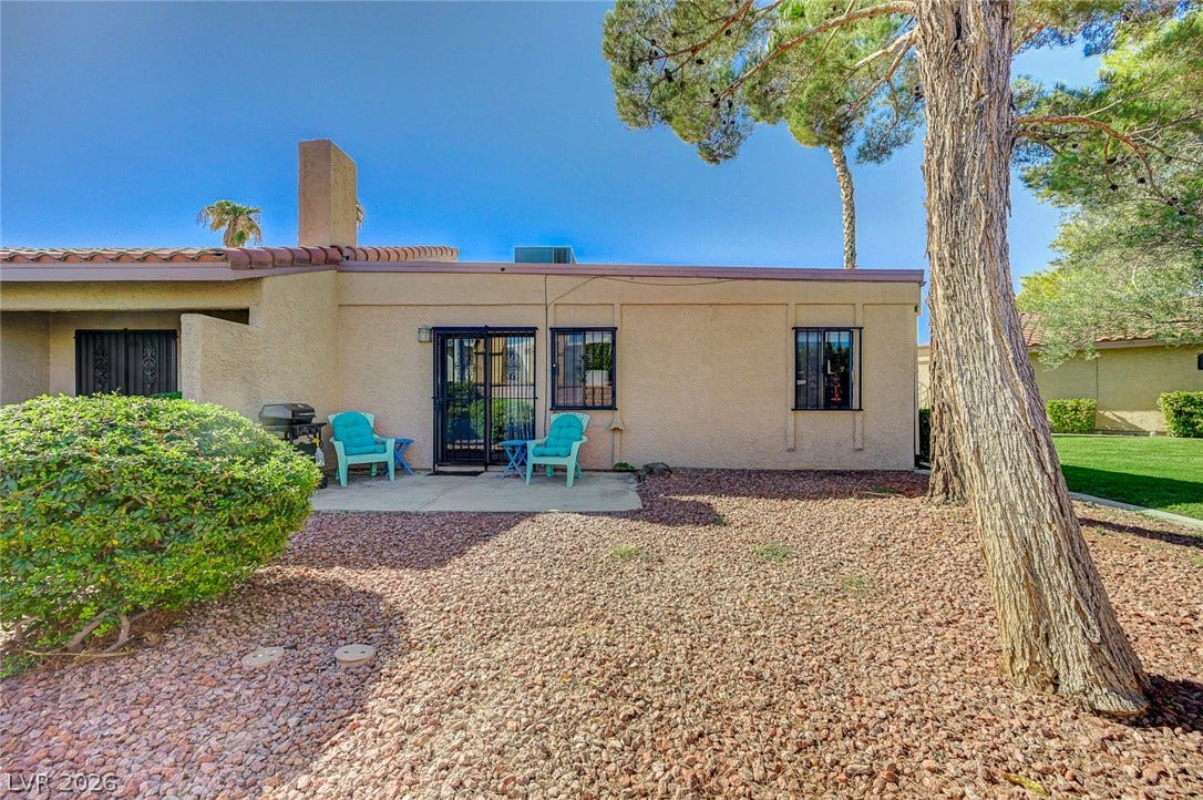 Mature trees frame the low-maintenance gravel yard and stucco exterior of this desert home.