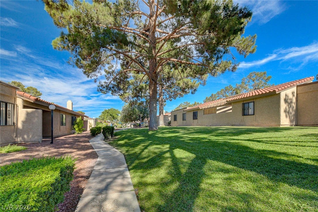 Manicured lawns and mature shade trees border the paved pathways of this residential community.