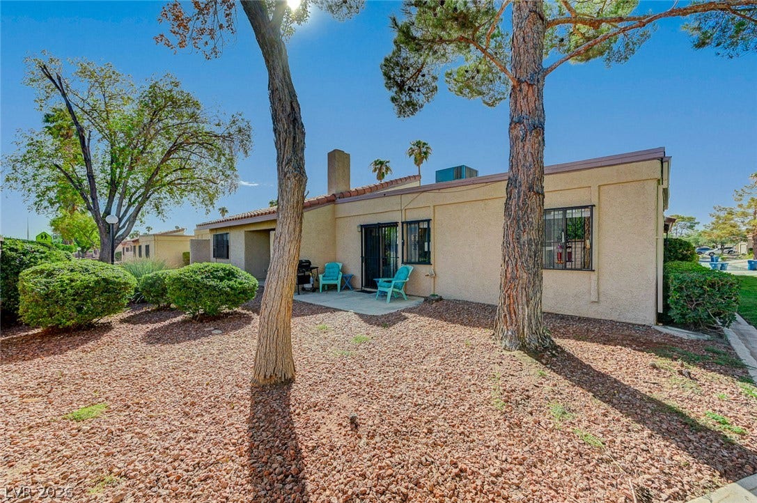 Mature trees shade a low-maintenance gravel yard bordering the back patio area.