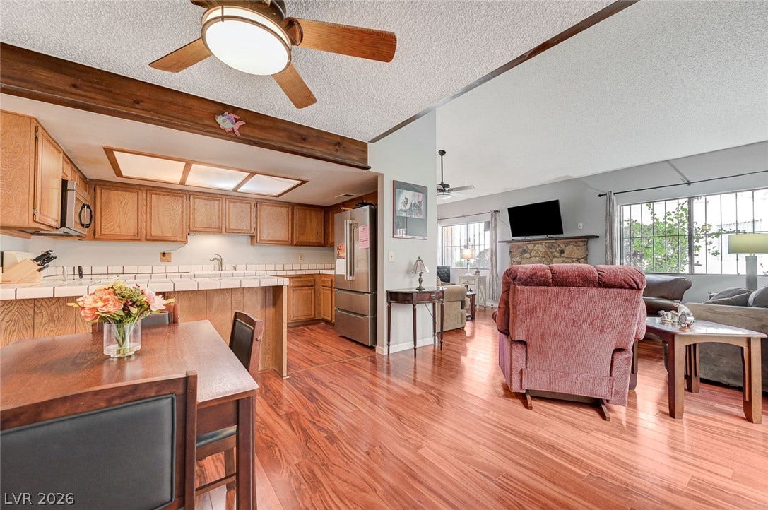 Rich wood floors seamlessly connect the kitchen and living areas in this airy layout.