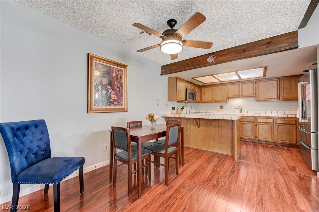 Rich wood flooring connects the comfortable dining area to the adjacent kitchen space.
