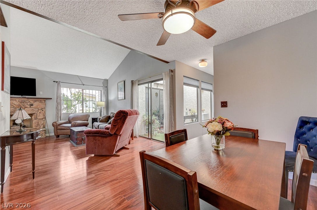 An open floorplan seamlessly connects the dining space to a vaulted living room with hardwood floors.