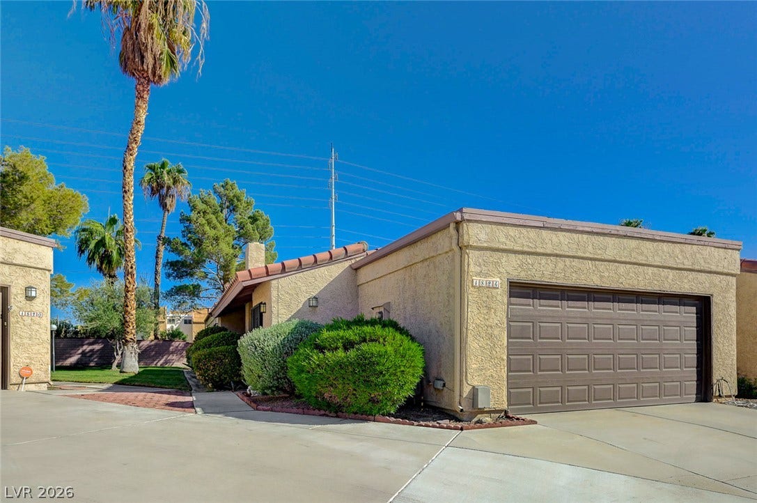 Desert landscaping and a paved driveway lead to this classic stucco exterior with attached garage.
