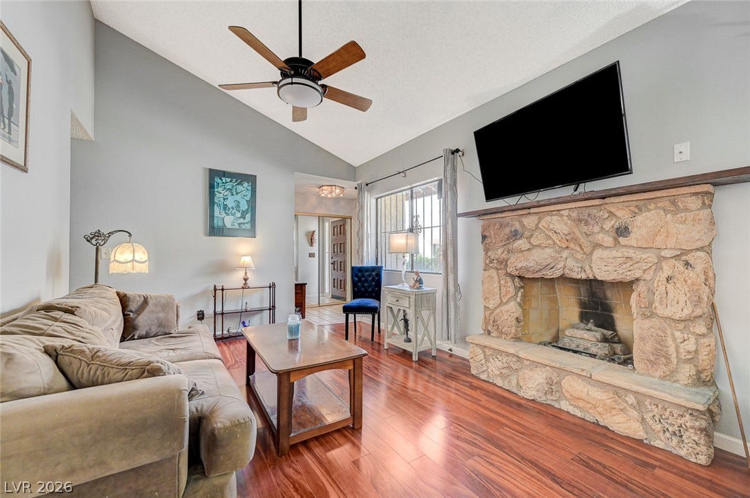 Rich wood floors and a vaulted ceiling elevate this warm living space with stone fireplace.