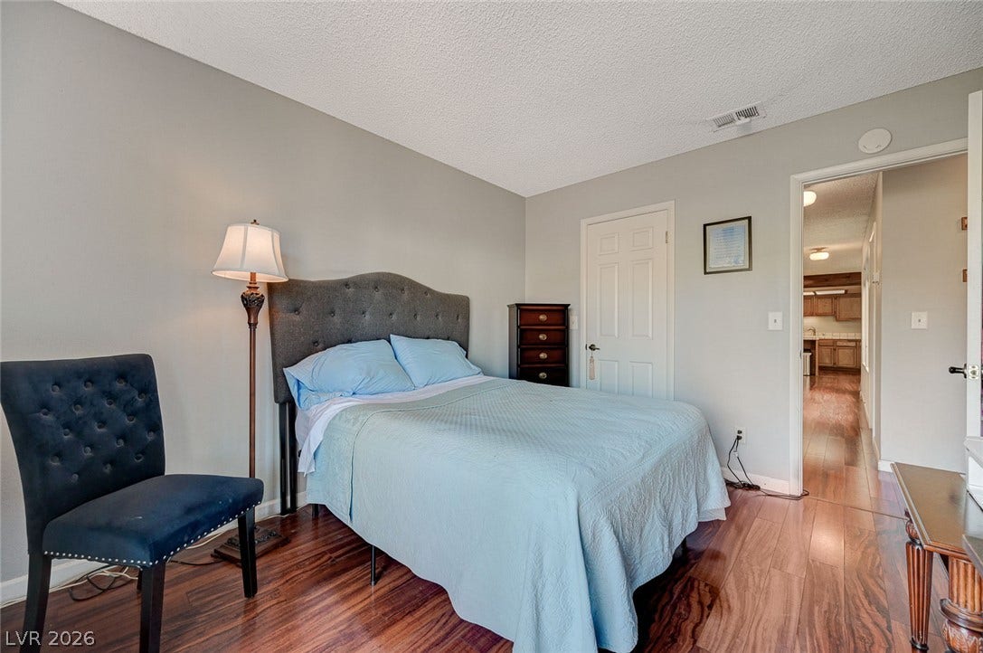 Rich hardwood flooring anchors this cozy bedroom, complete with a direct hallway connection.
