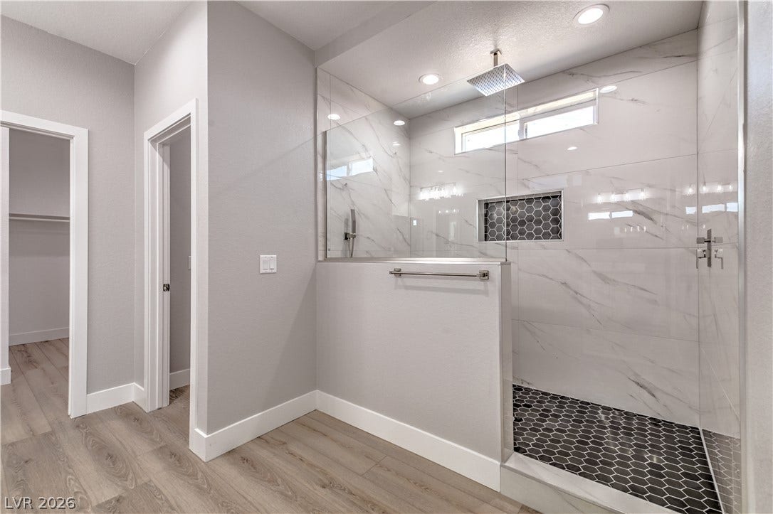 Full bathroom featuring a marble finish shower, a spacious closet, light wood finished floors, and recessed lighting