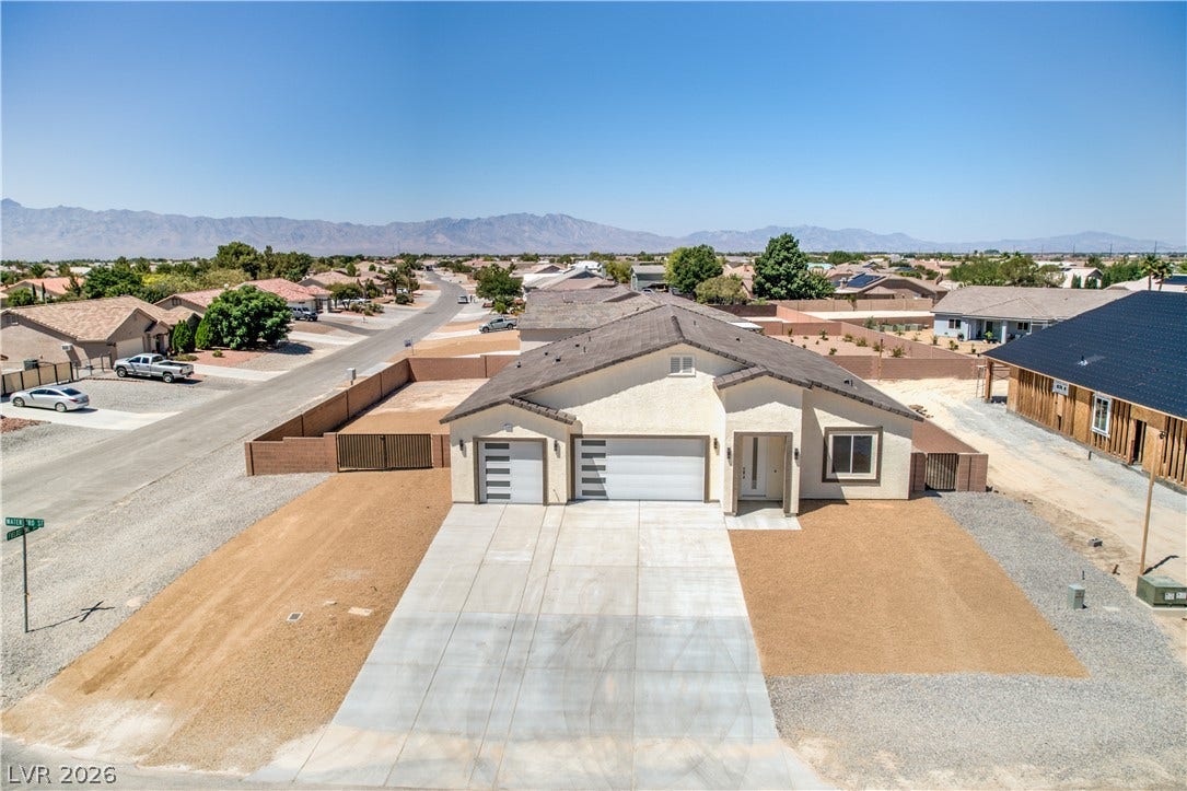 View of front of house featuring an attached garage, a residential view, stucco siding, a mountain view, and driveway