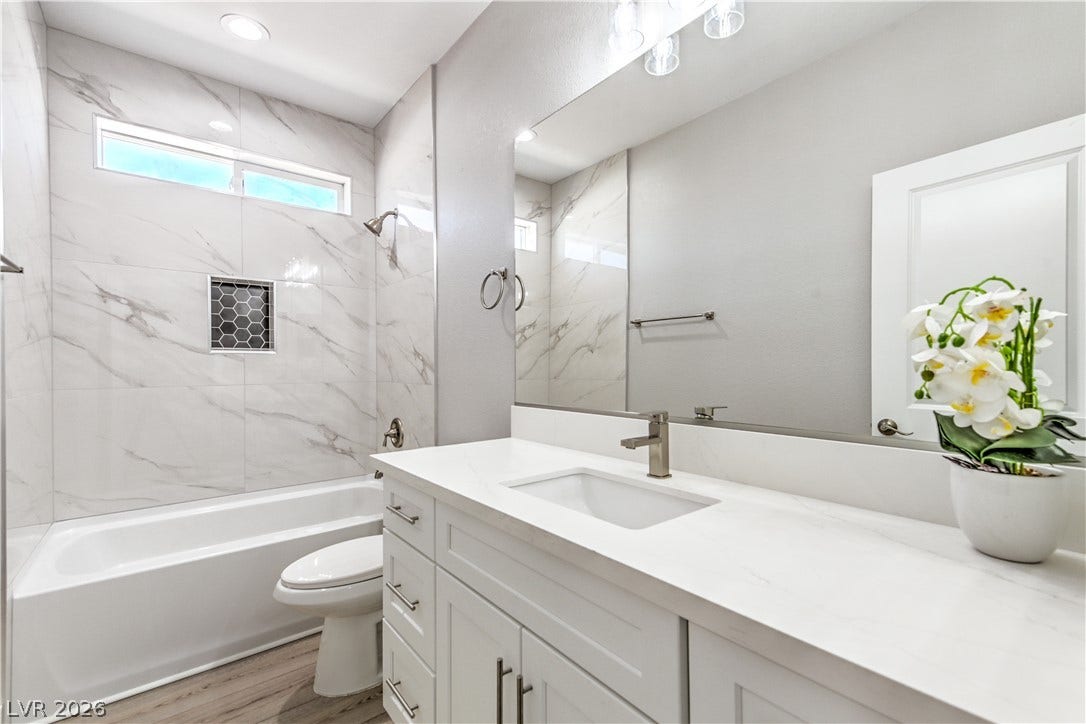 Bathroom with vanity, a combined bath / shower with marble appearance, and light wood finished floors