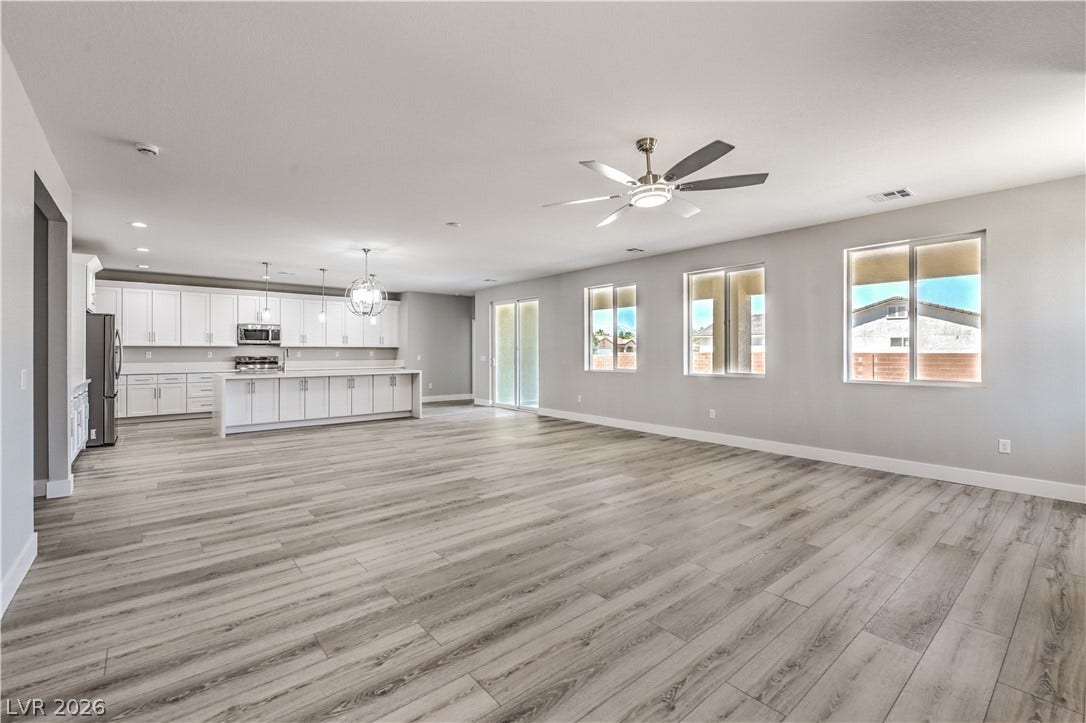 Unfurnished living room with light wood finished floors, a chandelier, and a ceiling fan