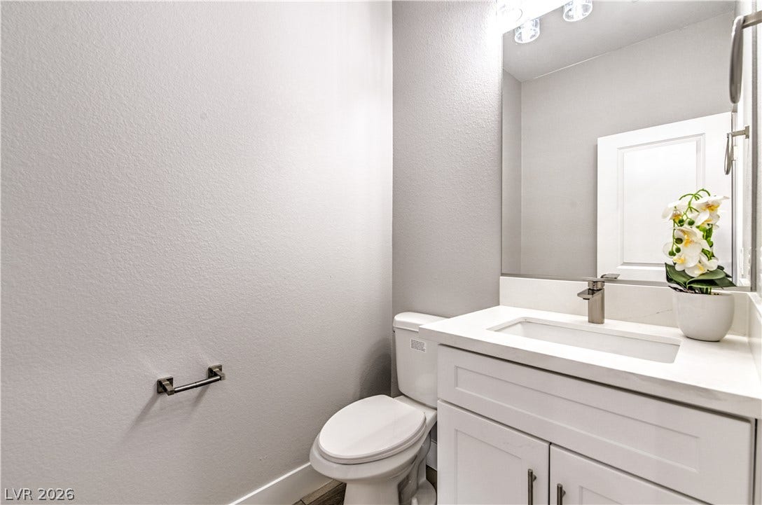 Half bath featuring a textured wall and vanity