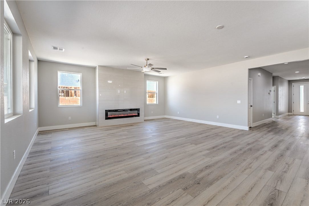 Unfurnished living room with plenty of natural light, a fireplace, light wood-type flooring, and ceiling fan