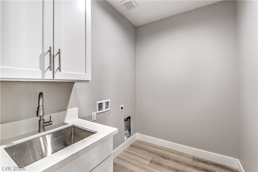 Washroom with light wood finished floors, washer hookup, hookup for an electric dryer, and cabinet space
