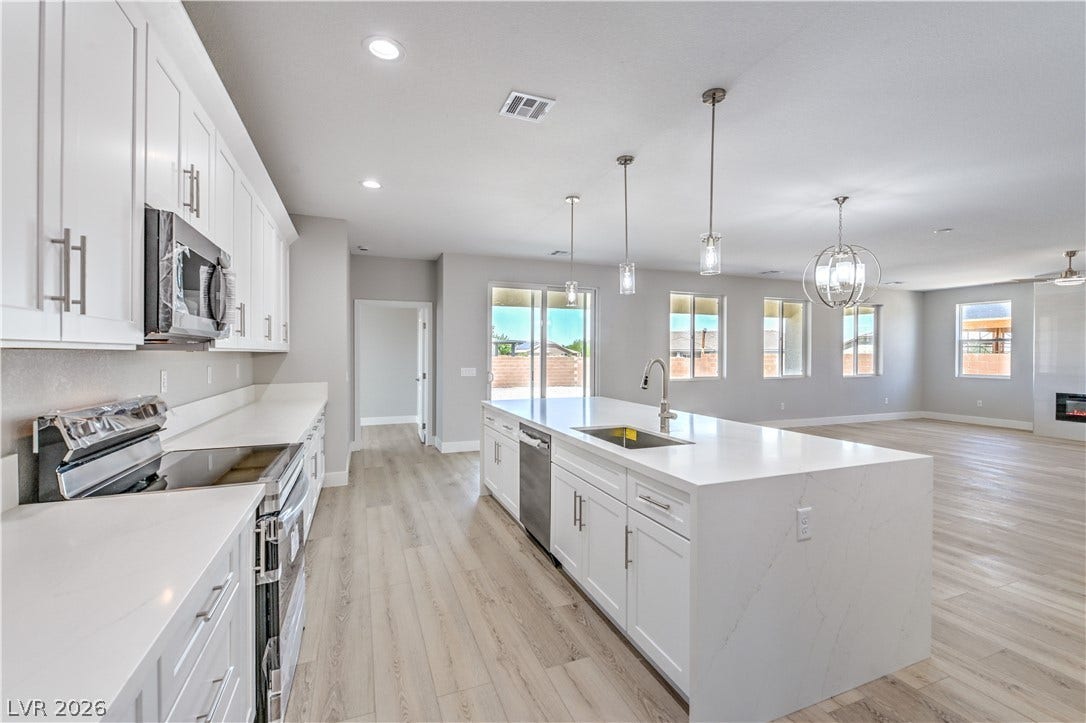 Kitchen featuring stainless steel appliances, white cabinetry, open floor plan, light wood-style flooring, and recessed lighting