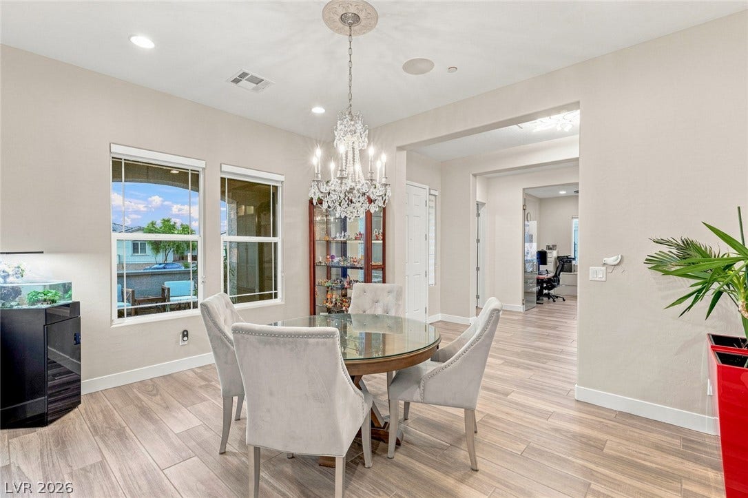 An elegant chandelier illuminates this formal dining area featuring wood-look tile flooring.