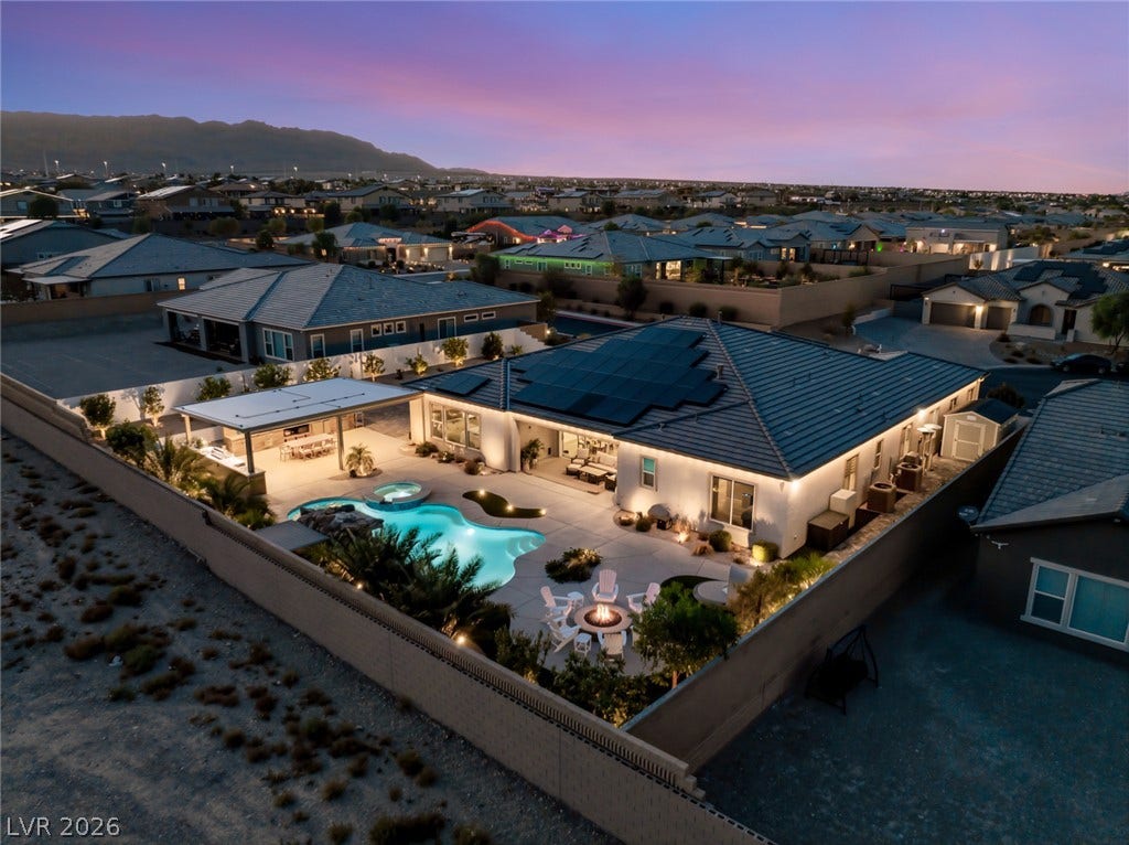 Dusk skies frame this backyard retreat, highlighted by a glowing swimming pool and fire pit.