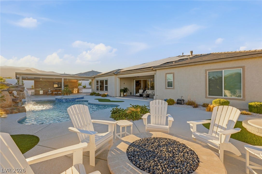 An inviting backyard oasis features a custom pool, waterfall, and matching stone fire pit.