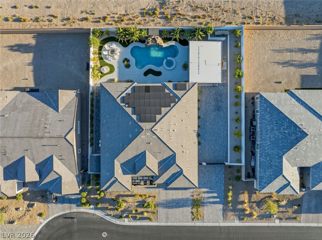 An aerial perspective reveals a modern residential property featuring solar panels, a pool, and manicured landscaping.
