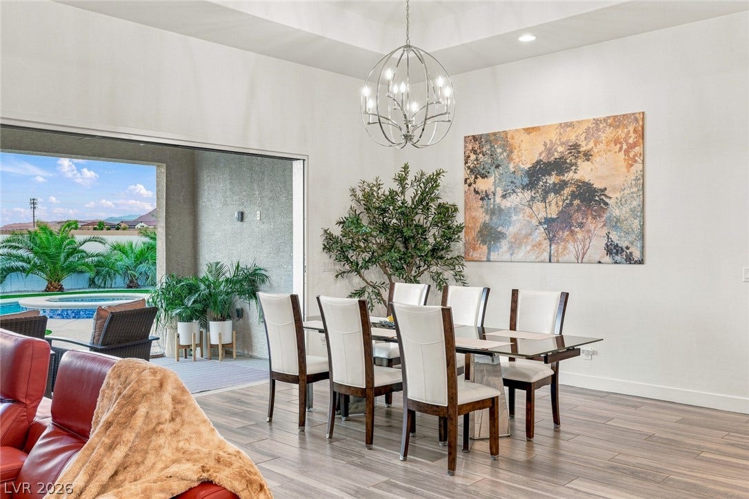 Recessed lighting and a distinctive sphere chandelier illuminate a modern dining space with sliding doors.