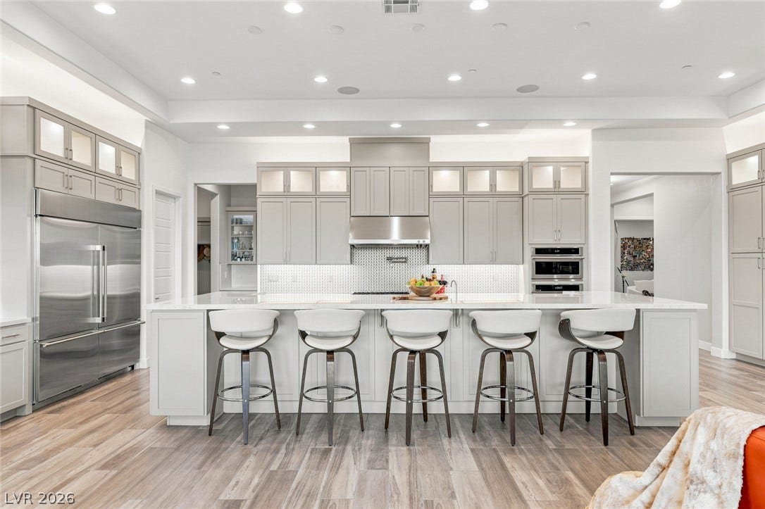 An expansive kitchen island anchors this culinary space featuring rich wood-look flooring and custom cabinetry.